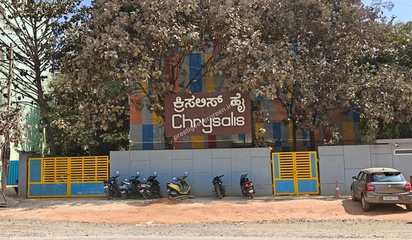 A comprehensive view of the Chrysalis High campus facade and boundary wall located near the Prestige Evergreen project site