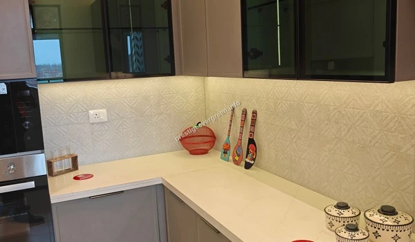 Close up view of a modern 3 BHK kitchen at Prestige Evergreen featuring a sleek black gas hob, white quartz countertop, and patterned tile backsplash