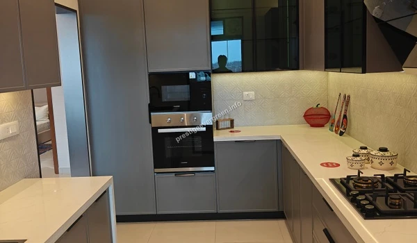 Wide view of the kitchen workspace in a 3 BHK apartment at Prestige Evergreen highlighting the seamless integration of storage cabinets and modern cooking appliances
