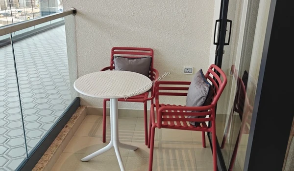 Private balcony area of a 3 BHK apartment at Prestige Evergreen featuring a modern coffee table and chairs for outdoor relaxation