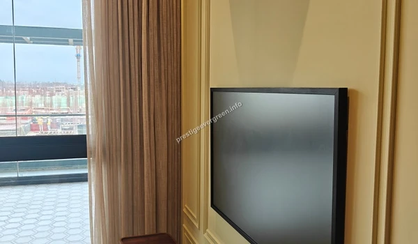 Sleek wall-mounted television screen in a bedroom at Prestige Evergreen with elegant wall molding and view of the balcony area