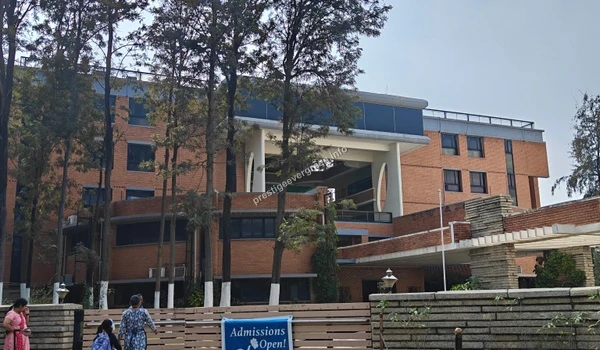 Exterior view of a large red brick educational campus building with trees near Prestige Evergreen