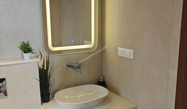 Designer bathroom vanity at Prestige Evergreen featuring a modern vessel sink, chrome wall-mounted faucet, and an LED-backlit mirror