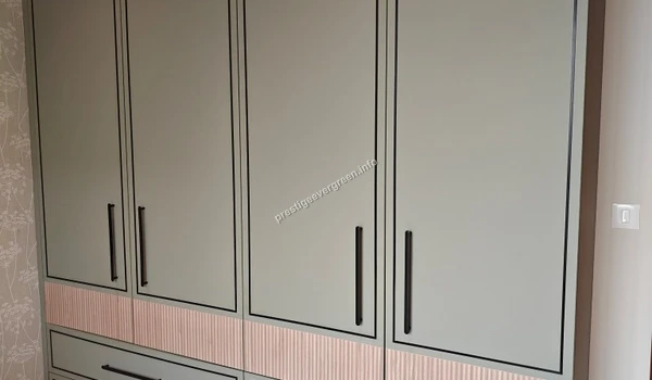 Modern four-door wardrobe at Prestige Evergreen featuring a muted sage green finish with elegant black handles and textured lower panels