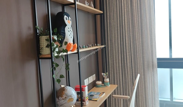 A modern study area at Prestige Evergreen featuring minimalist wooden shelving, decorative penguin plush, and creative workspace accessories