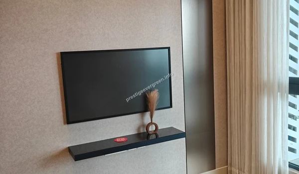 Sleek wall-mounted television installation at Prestige Evergreen featuring a minimalist floating black console shelf and elegant textured wall finishes