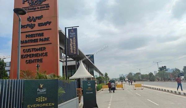 The designated entrance area for the Customer Experience Centre, highlighted by a large orange branding pillar and a 'Welcome' standee on the paved pathway.