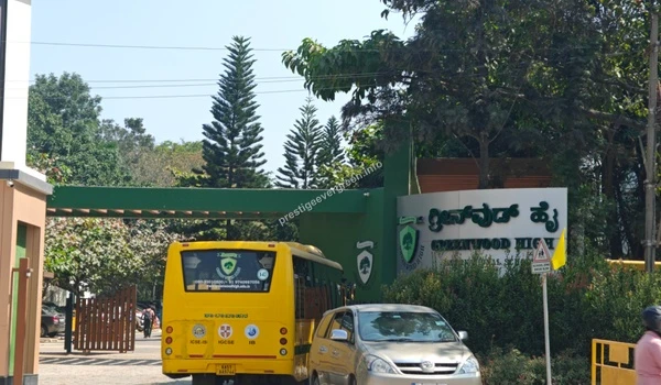 A perspective view of the Greenwood High International School entrance gateway featuring school buses near Prestige Evergreen