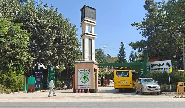 A perspective view of the Greenwood High International School entrance gateway with school buses near Prestige Evergreen