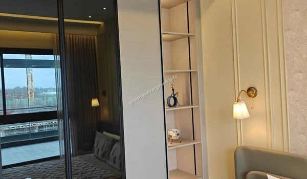 Close-up of integrated open shelving within a white wardrobe at Prestige Evergreen featuring warm accent lighting and decorative items