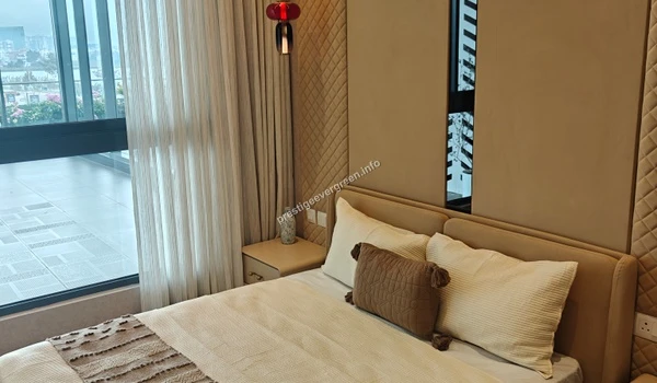 Primary bedroom suite at Prestige Evergreen featuring a designer quilted headboard, integrated bedside tables, and floor-to-ceiling windows for natural light