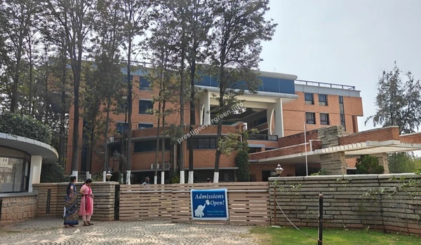 Exterior view of a modern school building with red brick architecture and lush green surroundings near Prestige Evergreen