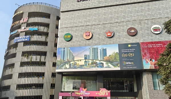 Exterior view showing the circular parking structure and fine-dining restaurants at Nexus Shantiniketan, an upscale lifestyle center near Prestige Evergreen.