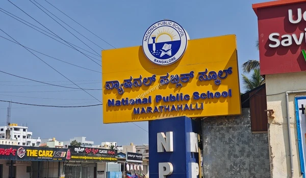 Angled view of the National Public School Marathahalli yellow signage board near Prestige Evergreen