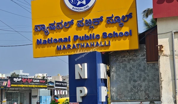Detailed view of the National Public School Marathahalli yellow name board near Prestige Evergreen