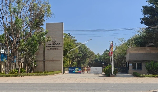 A wide exterior perspective of the Oakridge International School campus showcasing the surrounding greenery and infrastructure near Prestige Evergreen