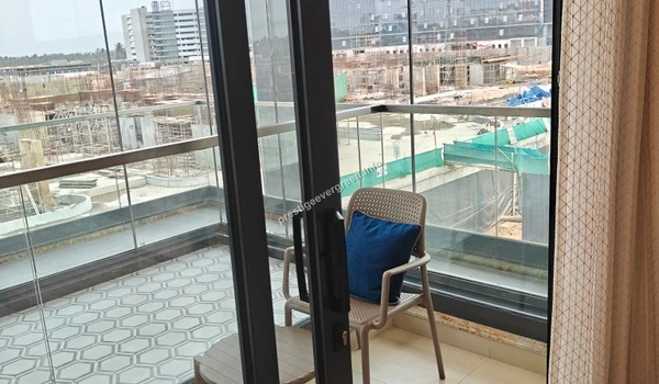 Spacious private balcony at Prestige Evergreen featuring glass railings, geometric floor tiling, and a view of the surrounding urban landscape