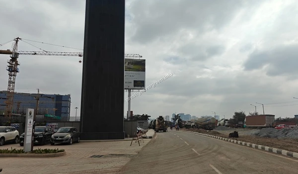 A vertical close-up of the black granite signage tower displaying the Prestige Evergreen branding, set against a cloudy sky at the site entrance.