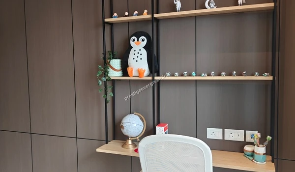 Modern study desk at Prestige Evergreen featuring wall-mounted wooden shelves, integrated lighting, and a minimalist grey office chair