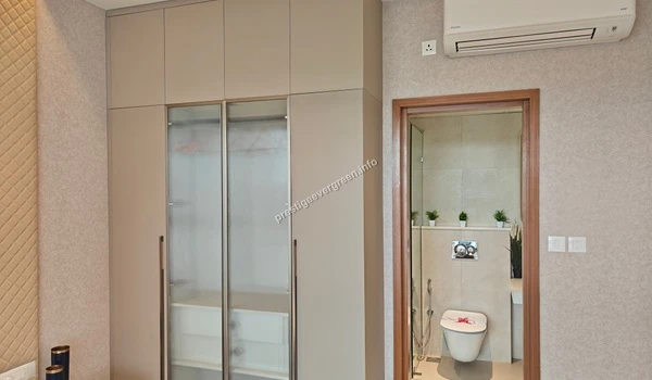 Bedroom view at Prestige Evergreen featuring a floor-to-ceiling integrated wardrobe with glass panels and a direct view into the modern en-suite bathroom